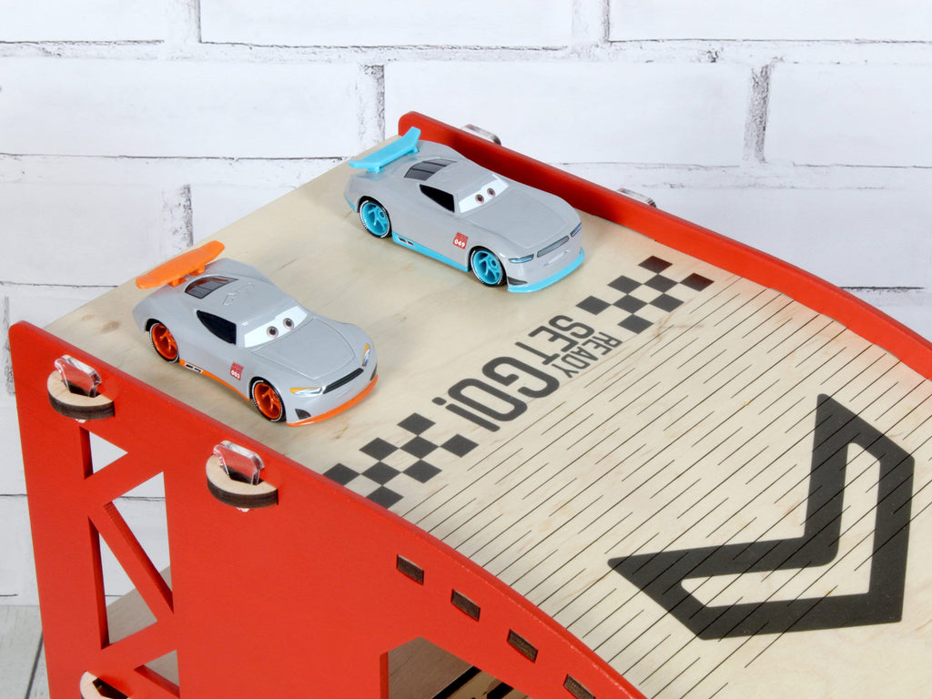 The toy car ramp with a variety of toy cars stored in its compartments, ready for play.